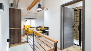 Un interior modern amb una escala, una zona d'estar amb cadires grogues i una zona de dutxa.