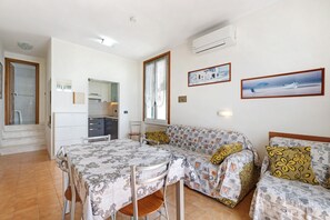 A compact living space with a dining area, kitchenette, and a sofa set.