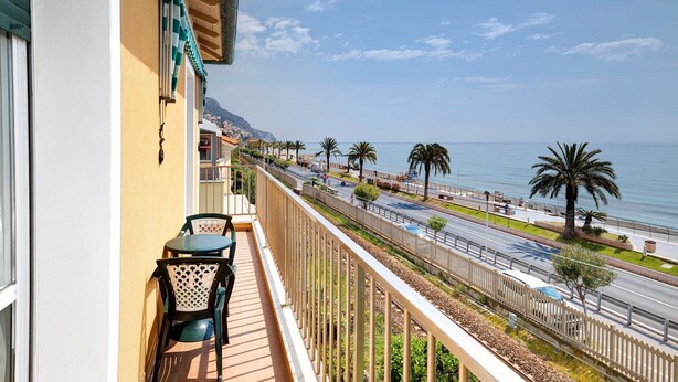 A balcony with a view of the sea, a road, and palm trees. - Holiday Apartment "Numero 7" with Sea View, 2 Balconies & Wi-Fi (Pietra Ligure)
