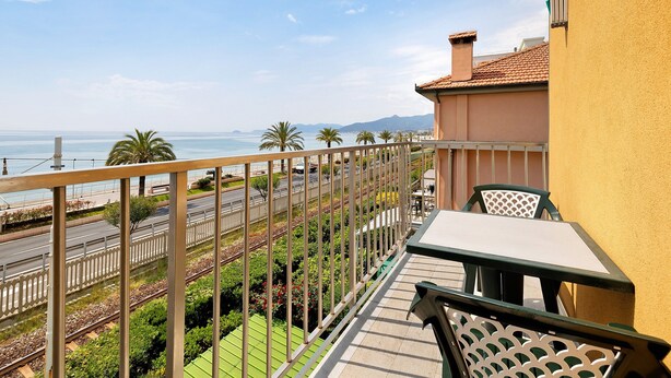 Un balcon avec vue sur l’océan, une table, des chaises et une rambarde.