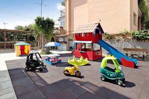 A children's play area with a slide, a small building, and toy cars.