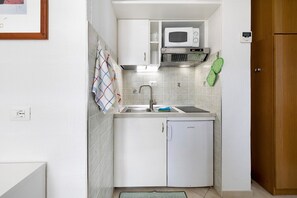 A compact kitchen with a microwave, sink, and a small refrigerator.