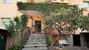 A building with a stone staircase leading to a door, a tree with yellow fruits, and a lounge chair. - Studio Apartment "Monolocale 12" with Sea View, Wi-Fi & Air Conditioning (Pietra Ligure)