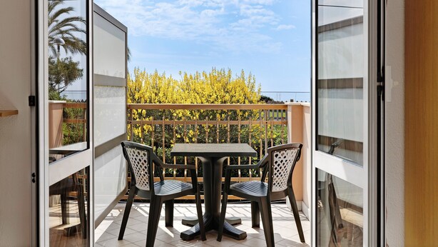 An open balcony with a table and chairs, a wooden fence, and a view of yellow foliage. - Holiday Apartment "Numero 14" with Sea View, Balcony & Wi-Fi (Pietra Ligure)