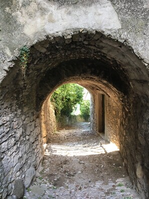 An arched stone passageway with rough walls and a cobblestone path. - Apartment 'Casa Maria' with Lake View, Private Garden and Wi-Fi (Brenzone sul Garda)