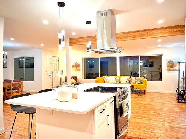Enjoy meals in the central island kitchen with a stovetop and oven, adjacent to a dining area with a table and chairs.