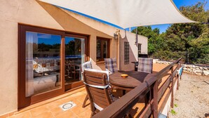 A patio area with a table and chairs, a wooden deck, and a large white shade sail. - Guest House 'Apartment Tina Capdepera' with Private Pool, Wi-Fi and Air Conditioning (Capdepera)