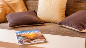 A magazine on a table, a couch with pillows, and a textured fabric background. - Guest House 'Apartment Tina Capdepera' with Private Pool, Wi-Fi and Air Conditioning (Capdepera)