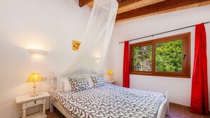 A bedroom with a bed, bedside lamps, a window with curtains, and a mosquito net. - Guest House 'Apartment Tina Capdepera' with Private Pool, Wi-Fi and Air Conditioning (Capdepera)