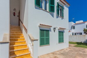 A white building with green shutters, a staircase, and a fire extinguisher.