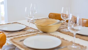 A dining table set with plates, cutlery, and wine glasses, with a bowl and a wooden rolling pin on the table. - Apartment 'Delfín 8' with Shared Pool, Wi-Fi, and Air Conditioning (Ciutadella de Menorca)