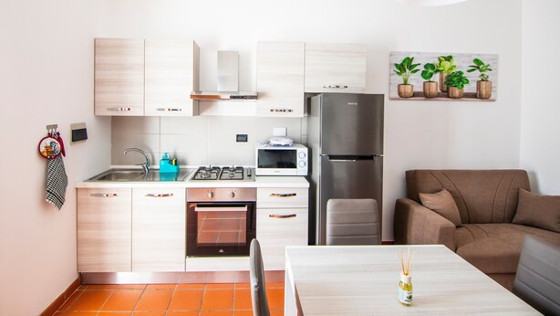 A compact kitchen with a refrigerator, microwave, stove, and oven. There is a dining table with a chair and a small plant on it. - Apartment 'L'Angolo di Torino' with Balcony and Wi-Fi (Torino)