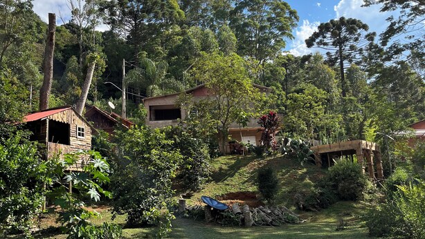 Un paysage rural avec une maison en bois, une antenne parabolique et une végétation luxuriante.