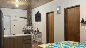 Une cuisine compacte avec des meubles en bois, un îlot central et une table à manger recouverte d’une nappe à motifs floraux.