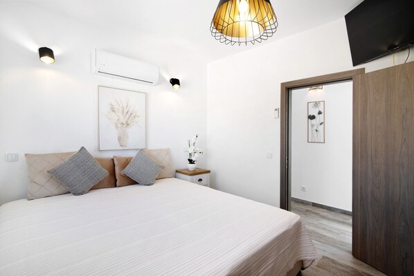 Une chambre à coucher avec un lit, une table de chevet, une lampe et une œuvre d’art.