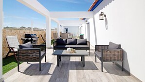 Um pátio externo com um sofá, cadeiras e uma mesa.