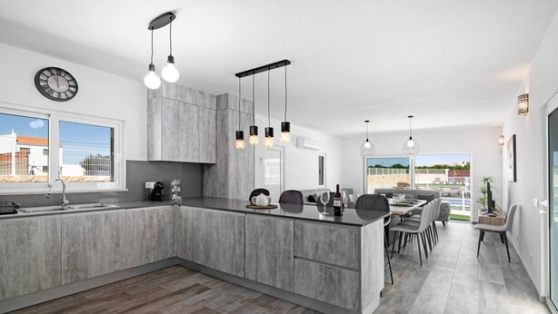 Cozinha moderna com uma ilha grande, luminárias pendentes e uma área de refeições com vista.