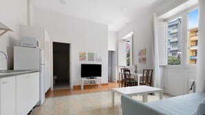 A modern kitchen with a microwave, a TV on a stand, and a dining area with a table and chairs.
