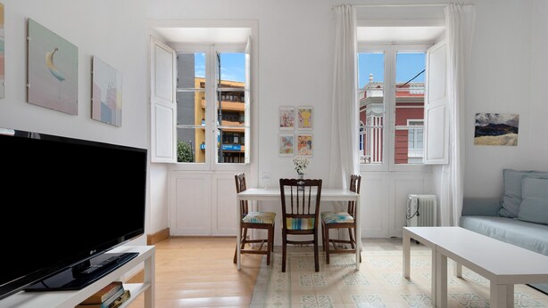 A living room with a TV, a dining table with chairs, a bench, and a sofa.