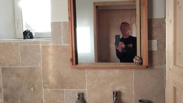 A bathroom with a large mirror, a sink, a towel rack, and a window.