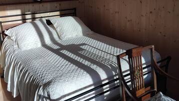 Una stanza con pannelli in legno, un letto, una sedia e una mensola.