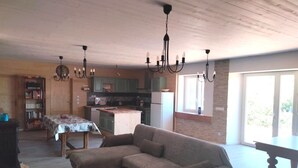 A living room with a sofa, a coffee table, a dining table, and a kitchen in the background.