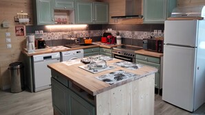 A kitchen with green cabinets, a wooden countertop, a stove, a microwave, and a refrigerator.