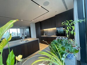 A modern kitchen with dark cabinetry, a central island, and a view of the city through large windows.