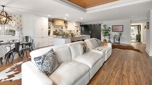 Een ruime woonkamer met een witte bank, houten vloeren en een plafondventilator.