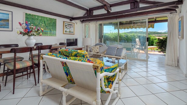 Amplia habitación con zona de comedor, un conjunto de sofás y vistas al exterior a través de un ventanal.