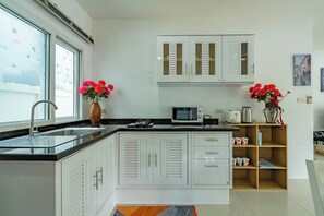 A modern kitchen with white cabinetry, a microwave, and a sink. - Star Private Pool Villa Peaceful 2 Br Tropical Hill (ตำบล ฉลอง)