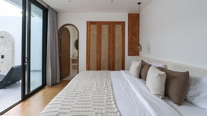 A bedroom with a large bed, a sliding glass door to a balcony, and a wooden wardrobe. - Villa Cactus Bingin (Pecatu)