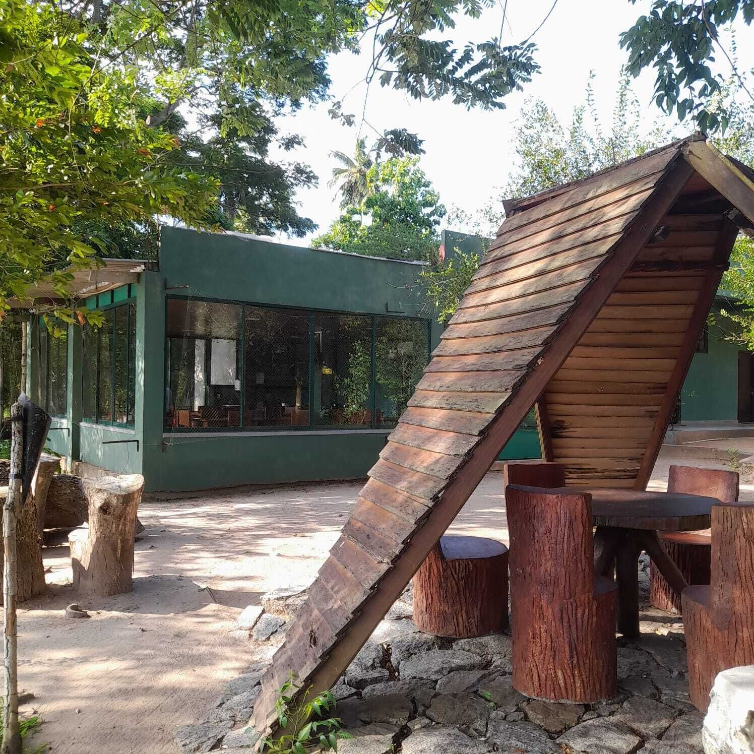 Un espacio de estar al aire libre de estilo rústico, con bancos de madera y una estructura de techo inclinado.