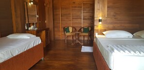 A wooden room with two beds, a small table, chairs, and a mirror.