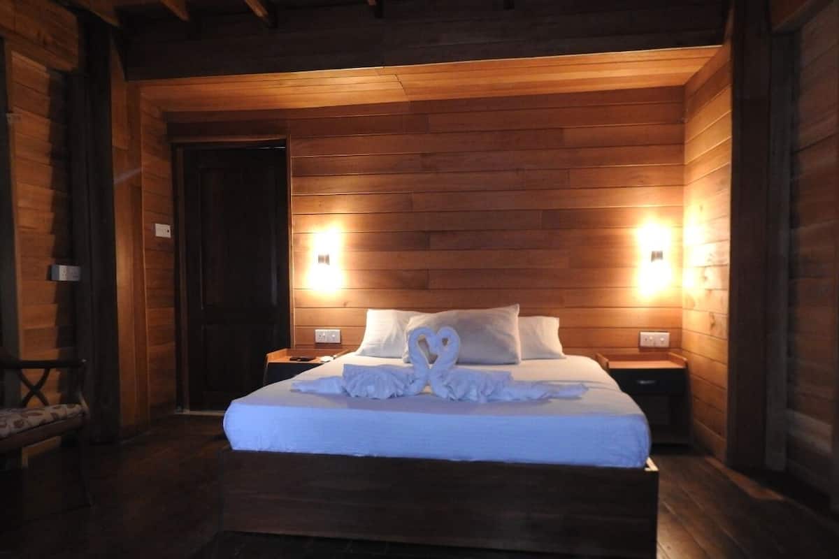 A wooden-paneled bedroom with a bed, two bedside tables, and a nightstand.