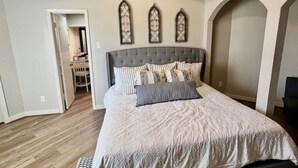 Un dormitorio con una cama grande, techo de madera y tres apliques decorativos.
