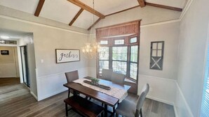 Un comedor con mesa y bancos de madera, una araña y una ventana con vistas.