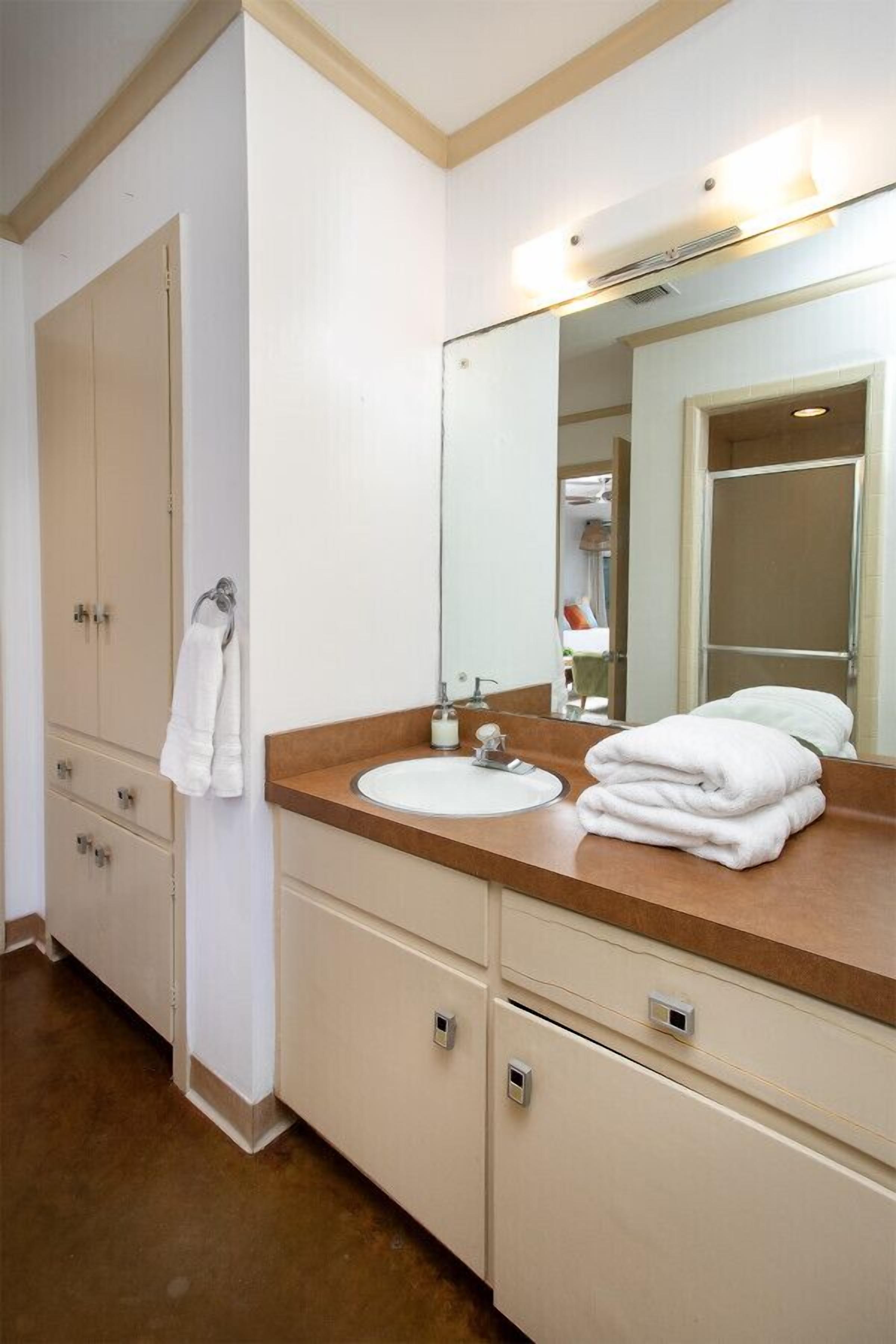 A bathroom with a sink, mirror, and towel rack.