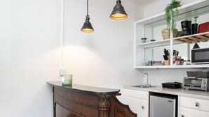 A kitchen with a wooden bar, two stools, a microwave, and a sink.