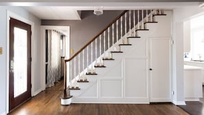 A staircase with white railings and wooden steps leading to a white door.