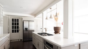 A modern kitchen with white cabinetry, stainless steel appliances, and pendant lighting.