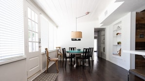 A dining area with a round table, chairs, and a hanging light fixture.