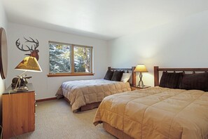 Un dormitorio con dos camas, una ventana y una lámpara sobre una mesita de noche.