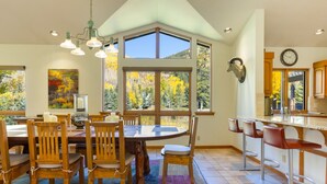 A spacious kitchen with a large island, wooden chairs, and a dining table set for six. - Large East Vail Home - Hot Tub & Steps to Bus Stop (Vail)