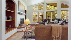 A spacious living room with a large window, a fireplace, and a cozy seating area. - Large East Vail Home - Hot Tub & Steps to Bus Stop (Vail)