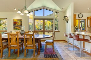 Una cocina amplia con una isla grande, varios ventanales y un comedor con sillas y mesa de madera.
