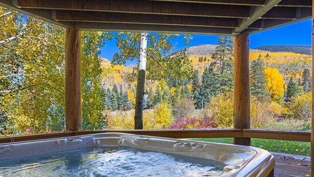 A hot tub with a wooden deck and a view of autumn foliage and mountains. - Large East Vail Home - Hot Tub & Steps to Bus Stop (Vail)