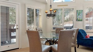 Un coin repas avec une table en verre, quatre chaises et un lustre.