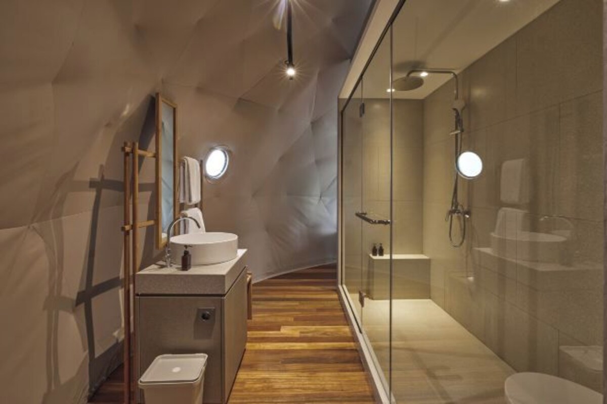 Een moderne badkamer met een houten wastafelmeubel, een glazen douchecabine en een inloopdouche.