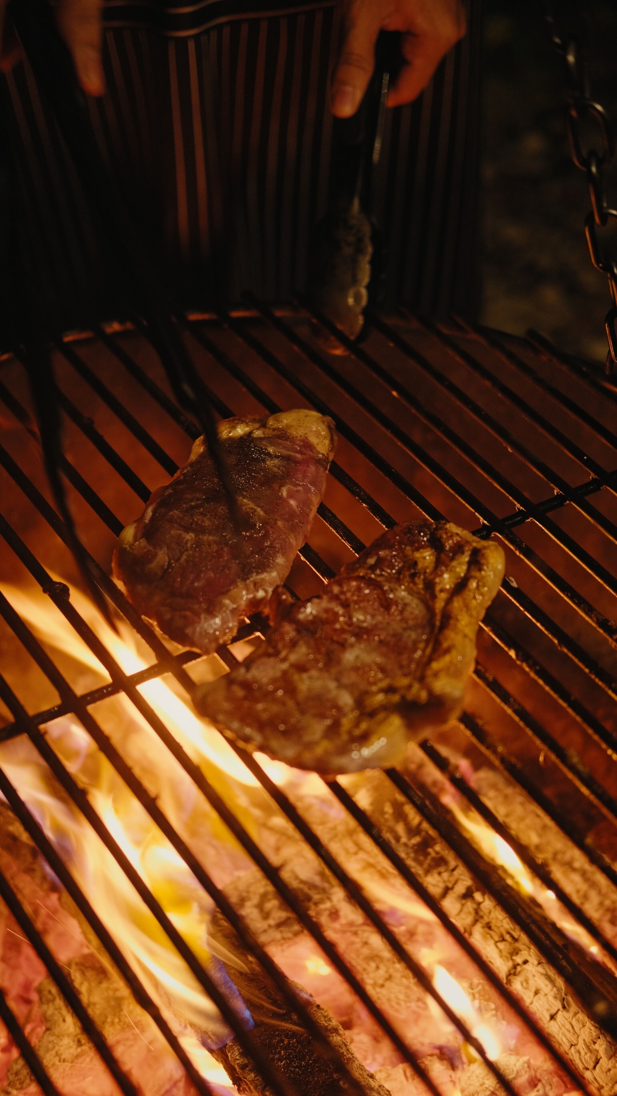 A grill with two burgers cooking over an open flame.
